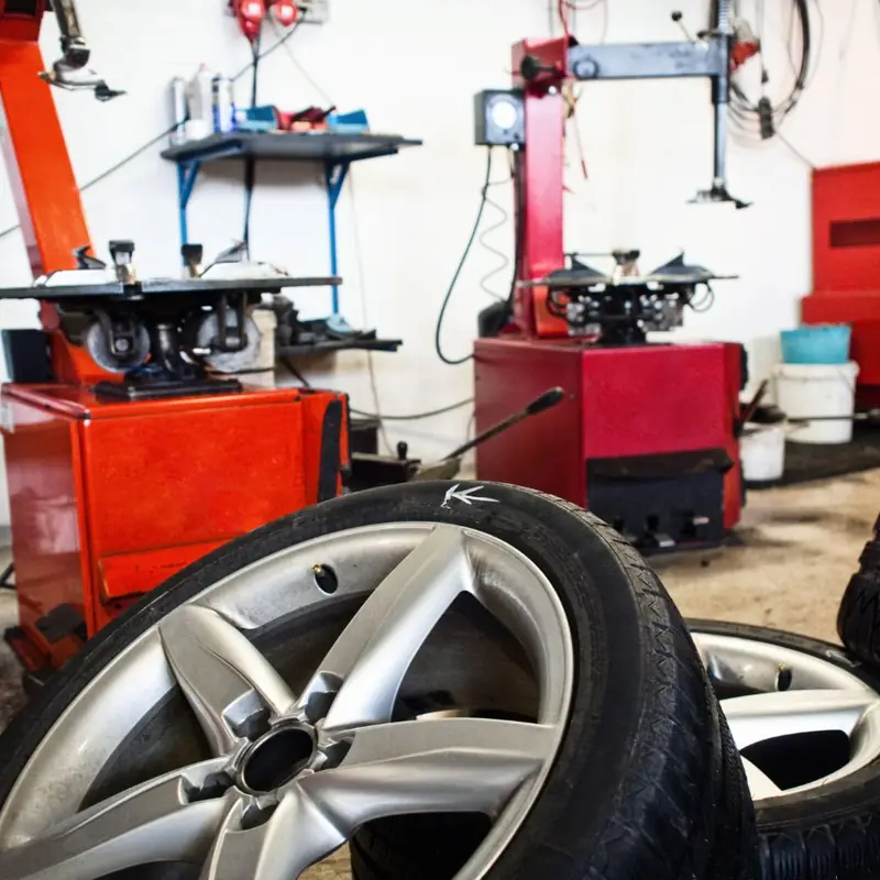 Red tire changer and wheel balancer inside the El Mecanico Auto Repair bay