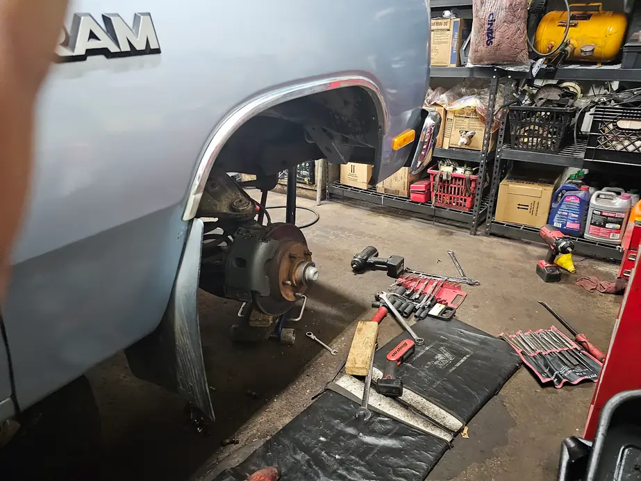 RAM truck with the front wheel off and tools laid out on the shop floor
